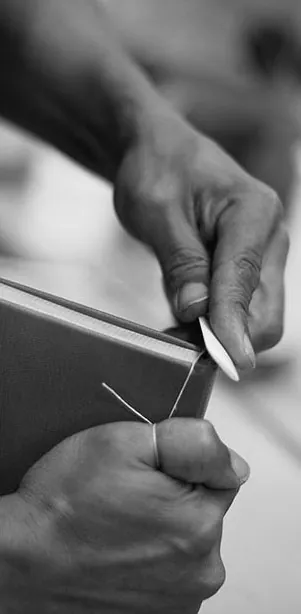 Hands sewing the sections of a book with needle and thread